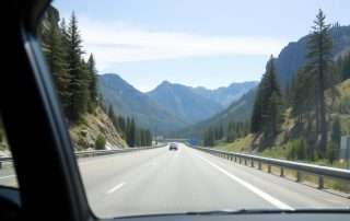 A car driving on a scenic road from Seattle to Crater Lake with mountains in the background
