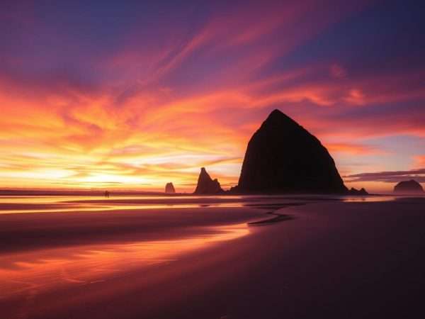 Cannon Beach at sunset with Haystack Rock silhouetted against orange sky