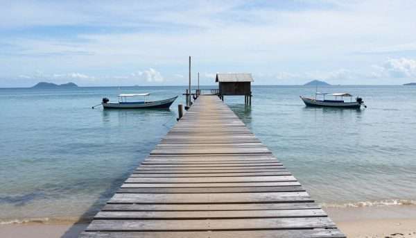 Long wooden pier of Koh Lanta Old Town extending into the Andaman Sea with mountains in the background Long wooden pier of Koh Lanta Old Town extending into the Andaman Sea with mountains in the background