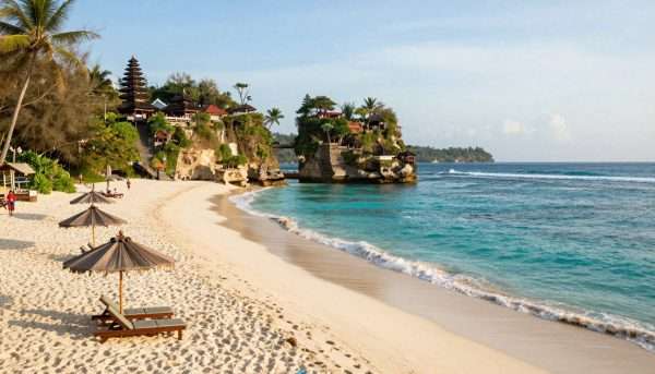 Panoramic view of Geger Beach showing white sand, clear waters, and the iconic temple on the cliff