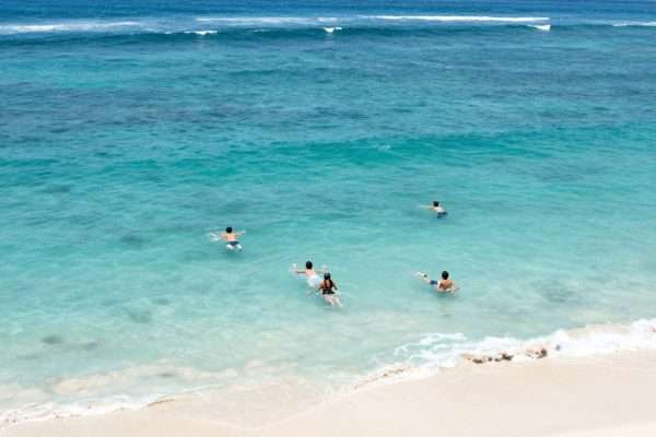 People swimming in the clear waters of Geger Beach People swimming in the clear waters of Geger Beach