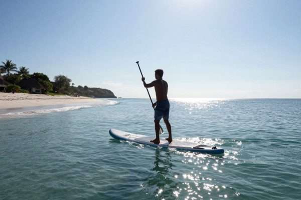 Person paddleboarding in the calm waters of Geger Beach Person paddleboarding in the calm waters of Geger Beach