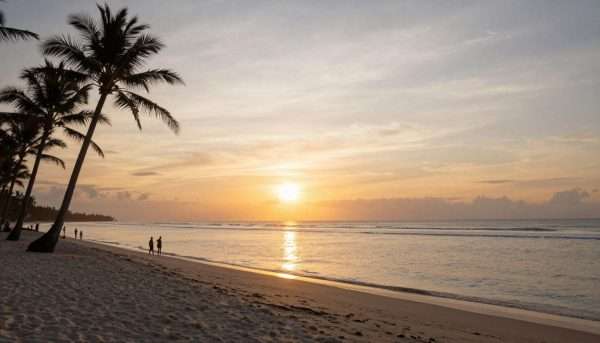 Sunset view of Geger Beach with silhouettes of palm trees and people enjoying the beach Sunset view of Geger Beach with silhouettes of palm trees and people enjoying the beach