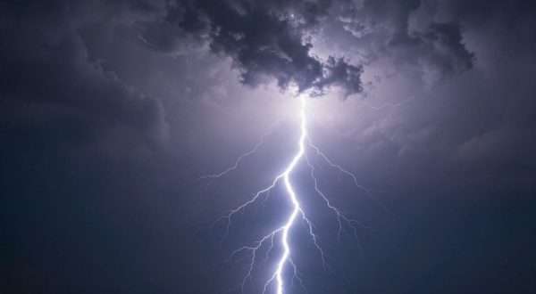 Dramatic lightning bolt striking during thunderstorm with dark clouds and electric atmosphere