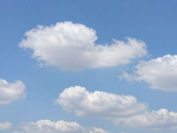 Fluffy white clouds in various shapes against bright blue sky creating peaceful scene