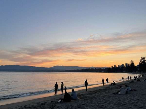 English Bay beach at sunset with people enjoying the waterfront English Bay beach at sunset with people enjoying the waterfront
