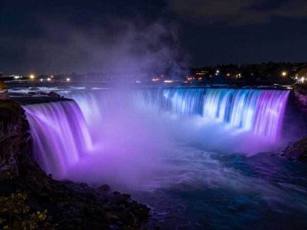 Niagara Falls illuminated at night with colorful lights Niagara Falls illuminated at night with colorful lights