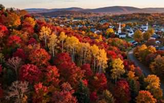 Vibrant fall foliage blanketing New England countryside with red, orange and yellow leaves